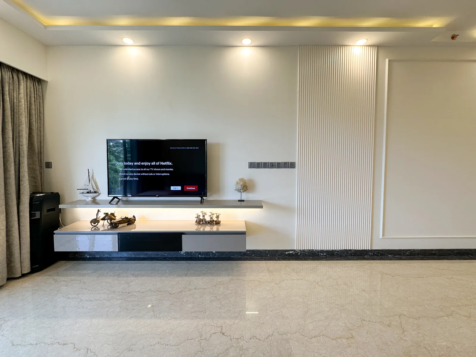 Living room TV wall with floating console and cove lighting — Somani's Residence